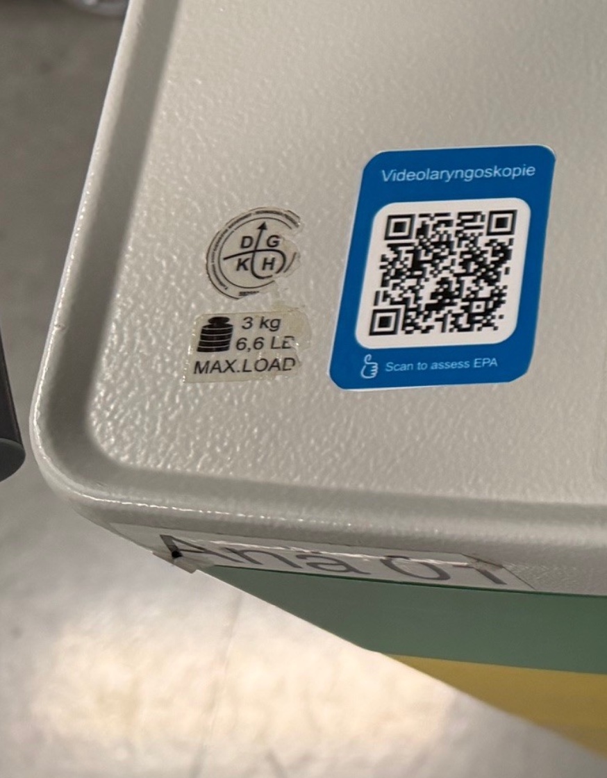 Blaue Aufkleber-Etikette mit QR-Code auf einem Gerät, Text Videolaryngoskopie und Scan to assess EPA